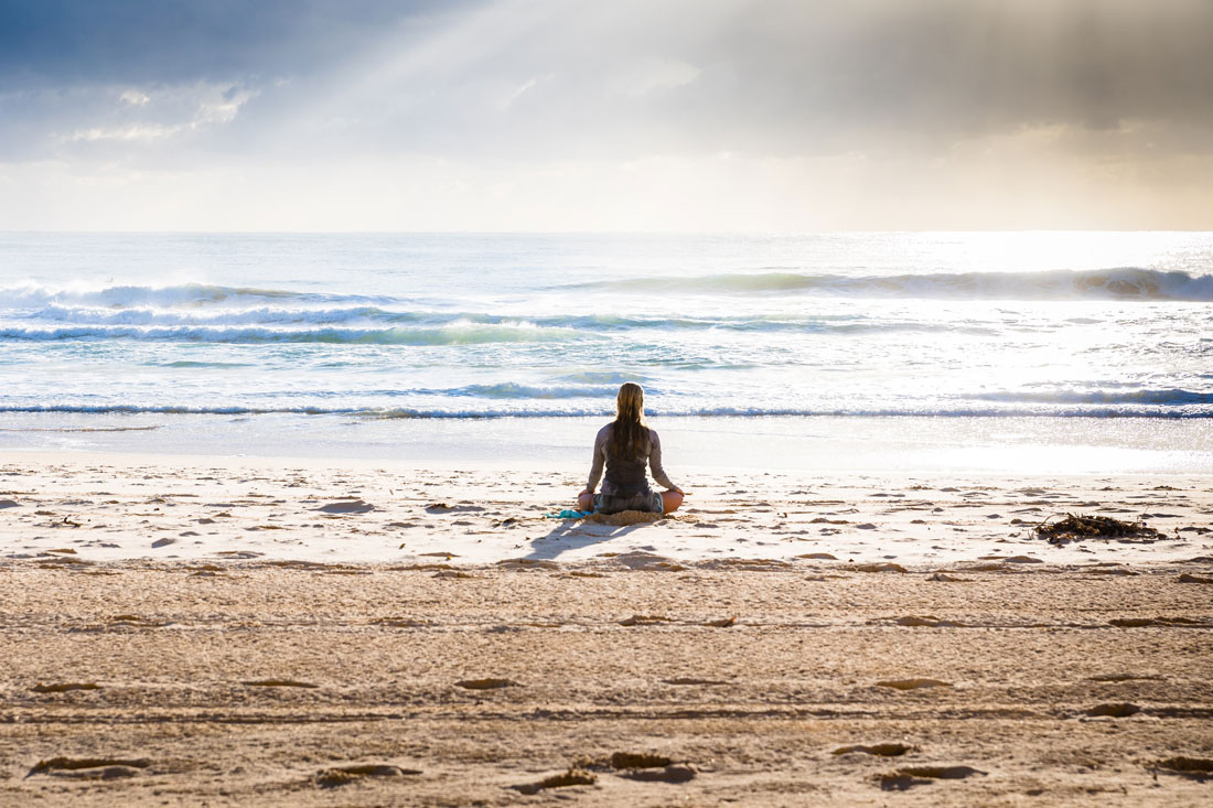 woman sitting on the beach doing yoga